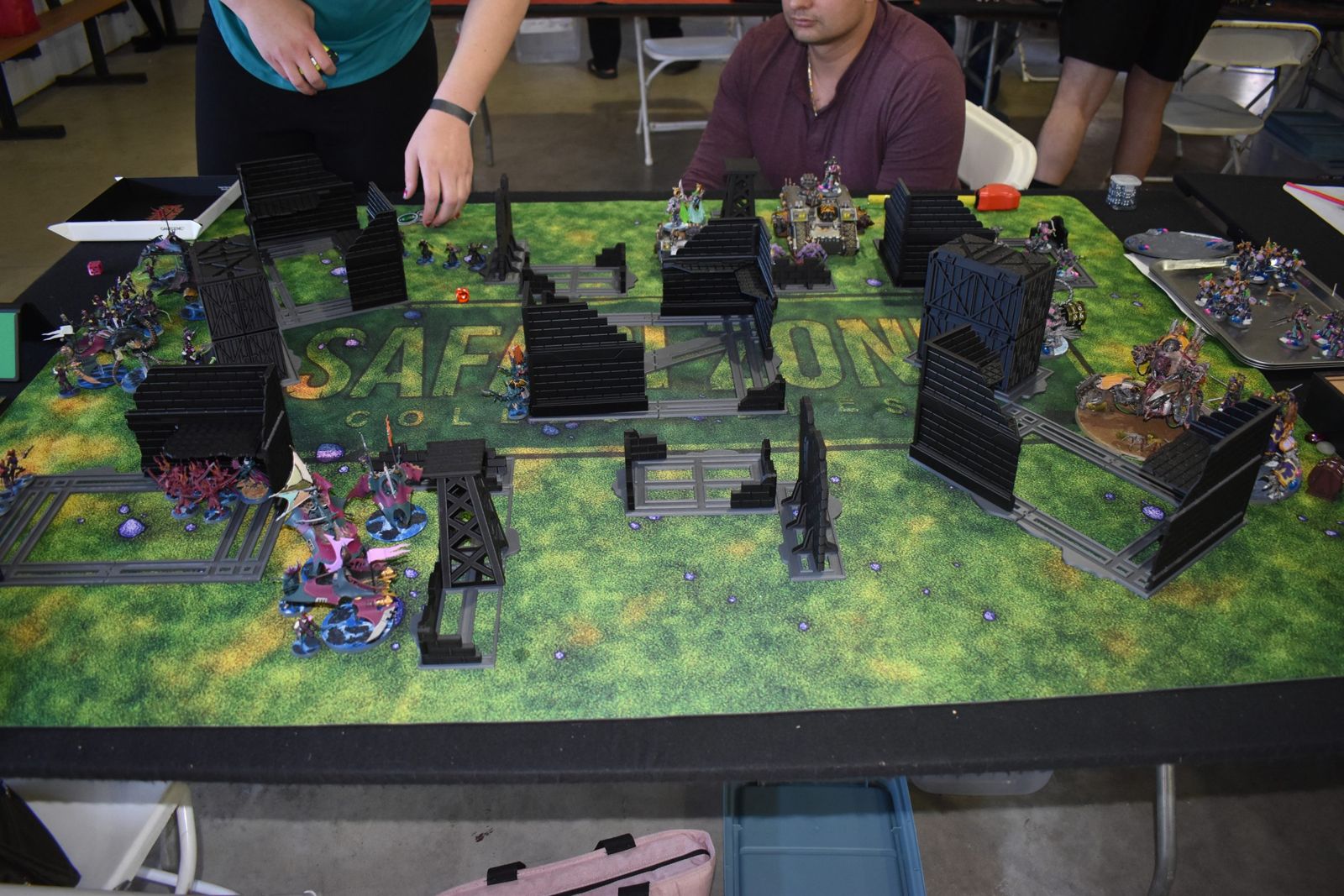 Painted armies fighting among 3D-printed terrain on a green battlefield mat